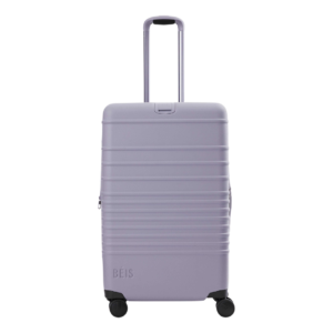 A sophisticated hard-shell suitcase in a gift guide featuring luxury travel accessories and gifts for women who travel.